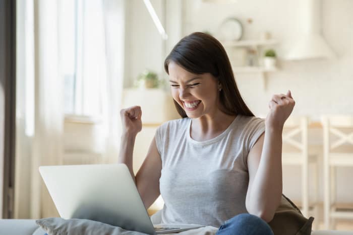 Kuvituskuva, jossa nuori nainen iloitsee läppiltä vastaanottamasta tiedosta.